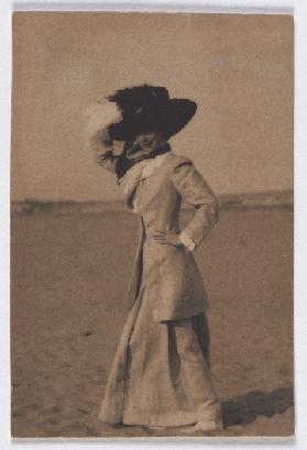 Young lady with big hat on the beach, de profil