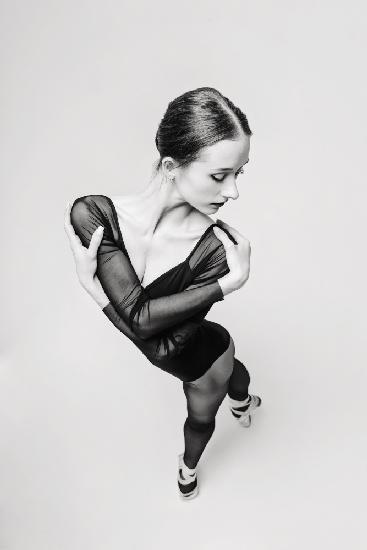 portrait of a ballerina in a black bodysuit top view standing with her arms around her shoulders