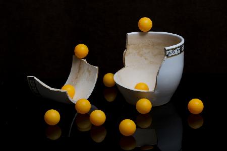 A broken vase with orange balls