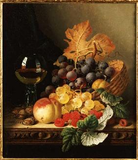 Ein Korb mit Weintrauben, Himbeeren, einem Pfirsich und einem Glas Wein.