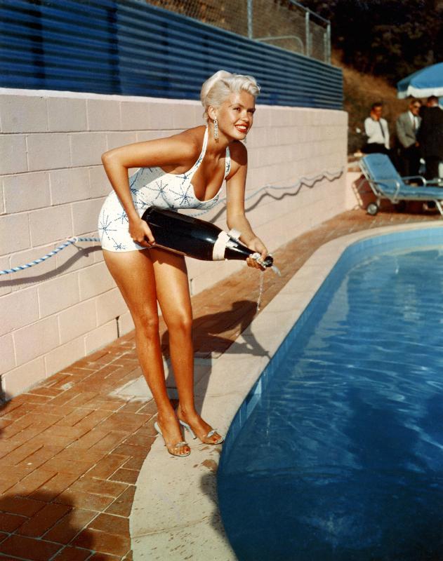 L'actrice américaine Jayne Mansfield avec une bouteille de champagne, près d'une piscine à Photographies de Célébrités