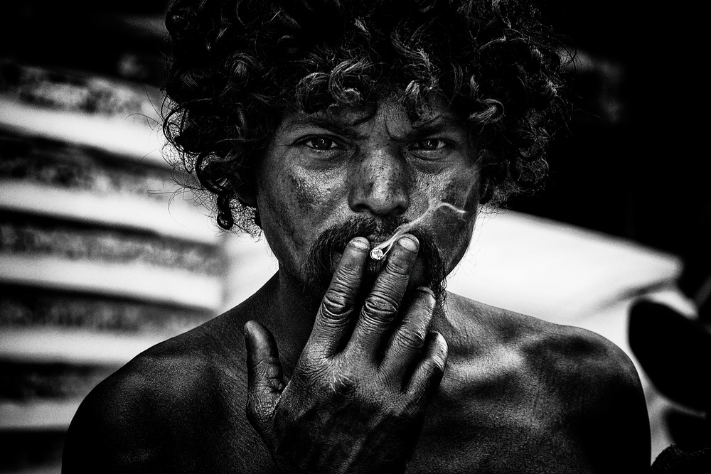 A homeless man smoking in the streets of Delhi. à Joxe Inazio Kuesta Garmendia