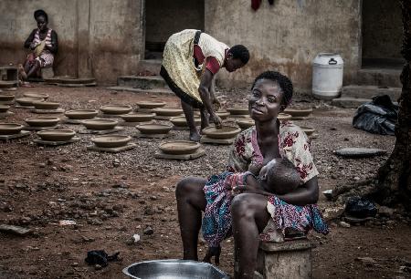A break in the making of pottery to breastfeed her child - Ghana