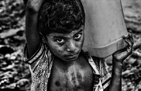 Refugee child carrying a container of water