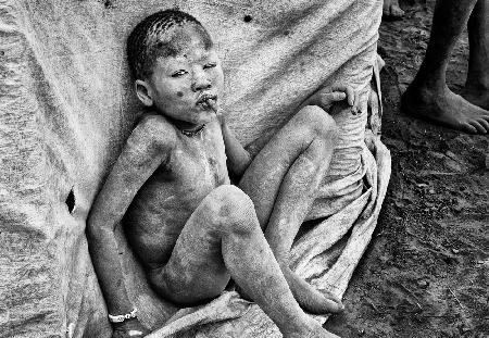 Mundari child playing with a bullet casing - South Sudan