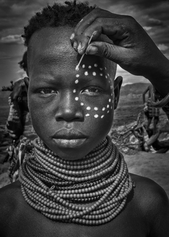 Painting the face of a karo tribe girl (Omo Valley-Ethiopia) à Joxe Inazio Kuesta