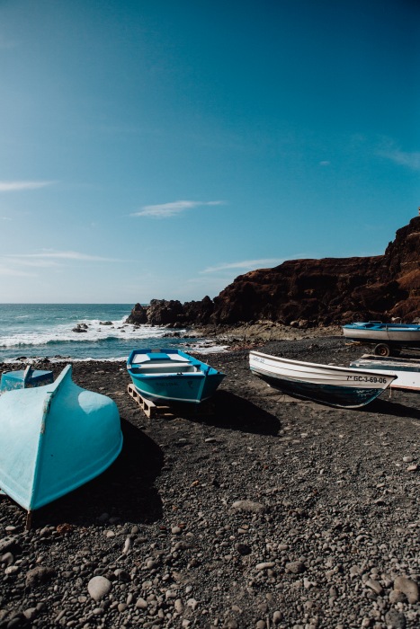 Blaue Boote auf schwarzem Vulkansstrand auf Lanzarote à Laura Nenz