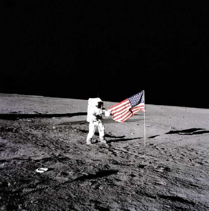 Apollo 12 Astronaut Charles Pete Conrad stands beside the United States flag after is was unfurled o à 