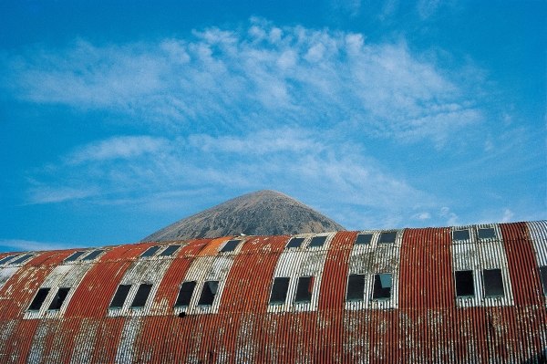 Rusted roof of a deserted warehouse with the breast of a mountain (photo)  à 