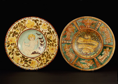 Two Della Robbia Wall Chargers, One Depicting A Putto Riding A Crescent Moon, The Other Designed By à 
