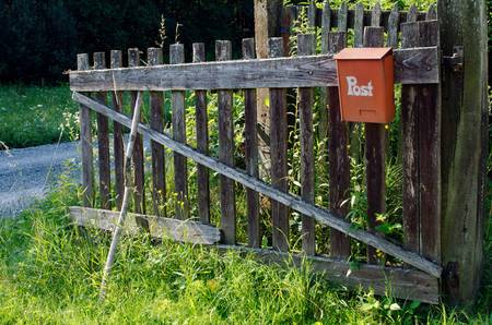 Holzzaun mit rostigrotem Postkasten