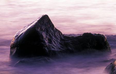 Meereswasser umfliesst ein Fels im Morgenlicht