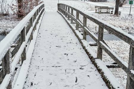 verschneite kleine Holzbrücke über eineem Bach